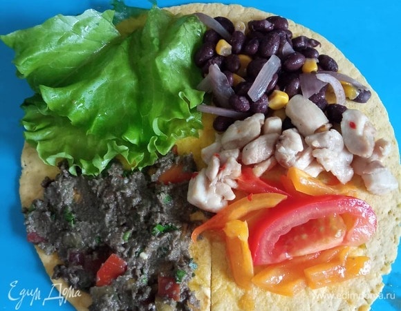 Теперь собираем тако. На сухой сковороде прогреваем лепешку. Выкладываем ее на доску. Делаем разрез ножом от центра вниз. По часовои стрелке на четвертинки лепешки выкладываем ингредиенты. Сначала гуакамоле (у меня он немного потемнел), потом лист салата, потом овощи и курицу в произвольном порядке. Сворачиваем, накрывая одной червертью другую по кругу: частью с гуакамоле накрываем часть с листом салата, потом эти две — на овощи, и последний раз вниз. Надеюсь, понятно объяснила, не нашла схему в интернете. Получается треугольник с несколькими слоями. Прогреваем на сухой сковороде. Снимаем со сковороды и добавляем внутрь сырный соус. Тако готово. Приятного аппетита!