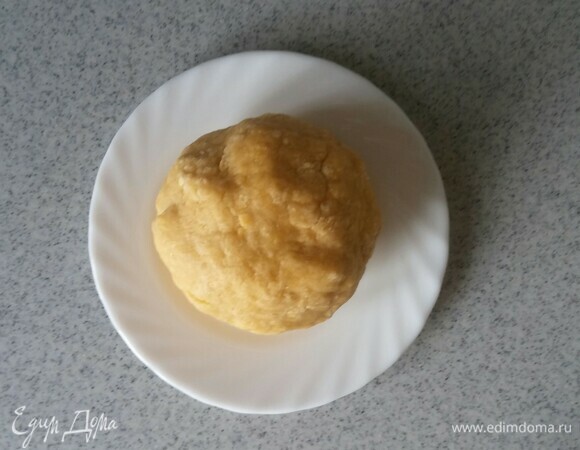 В глубокой емкости соедините соль, сахар, яйца и размягченное сливочное масло. Все перемешайте миксером до однородного состояния. Затем добавьте просеянную блинную муку и перемешайте все до состояния крошки, а после вымесите руками тесто до гладкости. Должен получиться шар, который не будет прилипать к рукам и стенкам емкости. Положите тесто на тарелку и уберите его в холодильник на 25 минут.