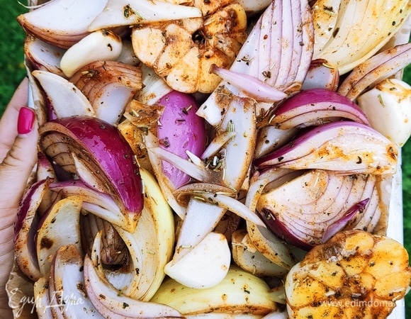 Лук нарезать на дольки, чеснок — пополам. Выложить все в глубокую миску и добавить соль, сахар, растительное масло, бальзамический уксус, сухой розмарин, прованские травы, сухой базилик. Хорошо перемешать. Выкладываем овощи на пергамент и ставим противень в духовку при 160–180°C, режим «верх/низ».