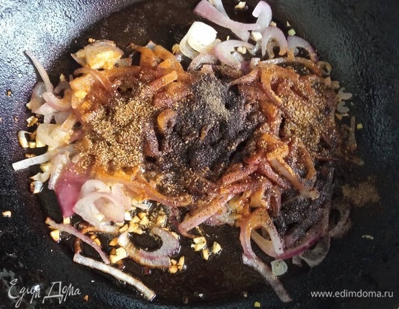 Готовим зажарку. Лук режем полукольцами или перьями. Лук можно взять и обычный репчатый, если нет красного. Чеснок измельчаем ножом или чеснокодавилкой. В разогретую с растительным маслом сковороду выкладываем лук и жарим 1 минуту. Добавляем чеснок, красный и черный перец и кориандр. Тщательно перемешиваем. Обжариваем полминуты.