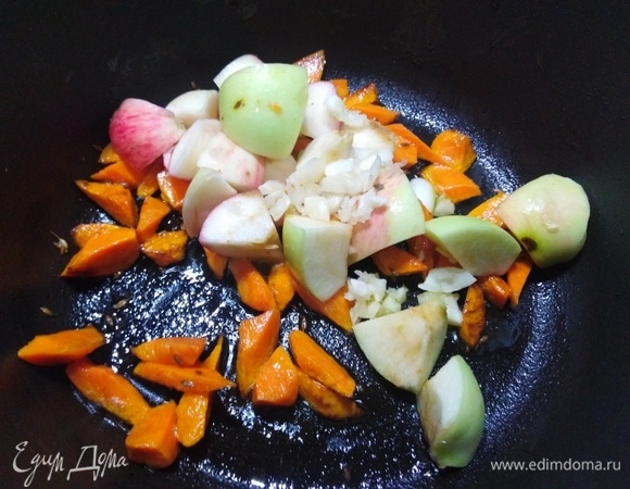 Добавьте нарезанные яблоки и рубленый чеснок. Жарьте, помешивая, 3–5 минут.