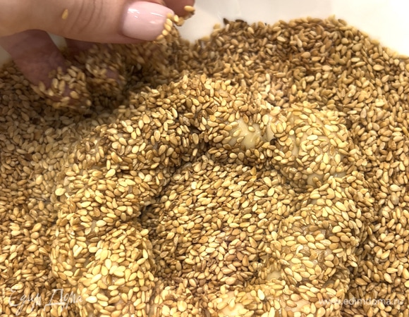 Смешать патоку (можно заменить медом) с водой, обмакнуть заготовки и запанировать в обжаренном кунжуте. Накрыть бублики и оставить на 20–30 минут.