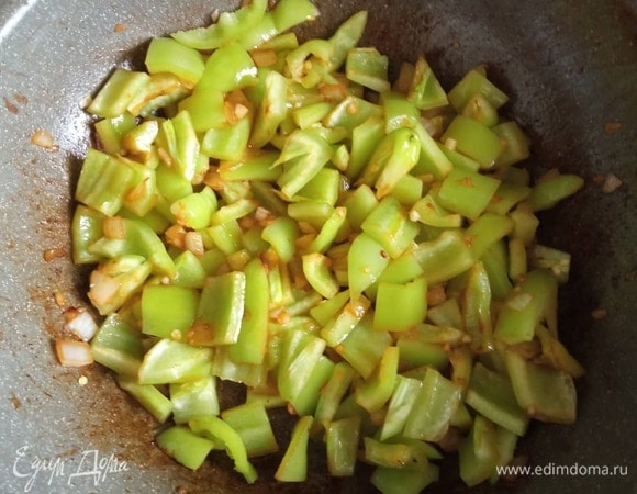 Мелко шинкуем лук и чеснок. Перец режем небольшими кубиками. В сковороду, где жарилась индейка, кладем лук, обжариваем две минуты, добавляем перец и через четыре минуты чеснок. Все жарим на среднем огне.