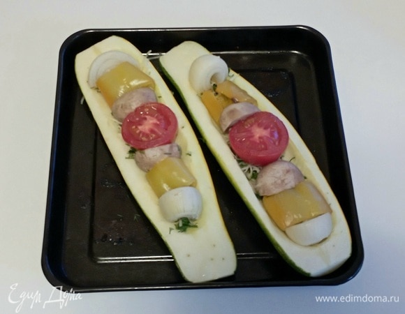 Положить в кабачковую лодочку нарезанные запеченые овощи и отварные шампиньоны. Для начинки потребуется весь запеченый перец и весь запеченый репчатый лук, но только один из запеченых помидоров и два отварных шампиньона. Еще один запеченый помидор и отварной шампиньон потребуются чуть позже.