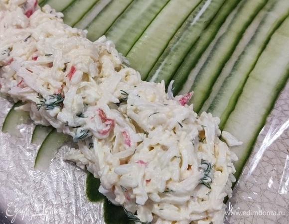 Огурец нарезала овощечисткой на тонкие слайсы. Выложила внахлест на полотенце, сверху накрыла пищевой пленкой. Пленку перевернула, чтобы огурцы остались на ней. Выложила по краю салат и завернула в рулет.