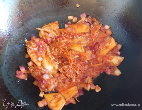 В воке нагреваем растительное масло. Обжариваем лук 1 минуту. Добавляем кимчи, жарим 2 минуты, постоянно помешивая.