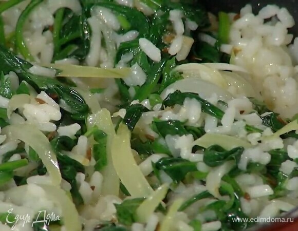 Выложить к луку со шпинатом готовый рис, влить горячий бульон, посолить, добавить нарезанную зелень и все перемешать.