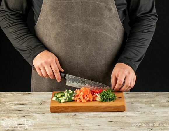 Огурец и помидор нарежьте кубиками. Перец чили мелко нарежьте. Петрушку и чеснок мелко порубите.