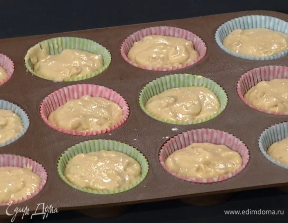 В формы для кексов вложить бумажные вставки и разложить тесто, наполняя их на половину объема.