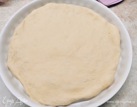 Подошедшее тесто раскатайте в лепешку, накройте полотенцем и оставьте на 20 минут.