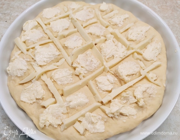 Для начинки смешайте мягкое сливочное масло с чесноком (натрите его на мелкой терке). Сыр нарежьте брусочками. На подошедшей лепешке сделайте надрезы в виде решетки. В надрезы поместите сыр, а квадратики смажьте чесночным маслом.