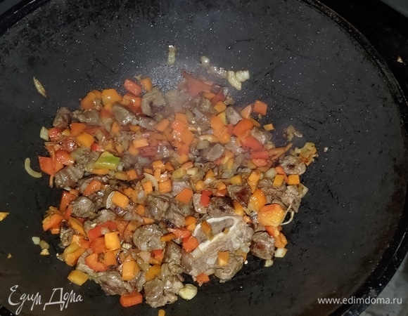 Сильно разогреть масло в казане и обжарить мясо до небольшой корочки, регулярно помешивая. Далее добавить лук и обжарить 3–4 минуты, добавить перец сладкий и чили, обжарить минуты 3.