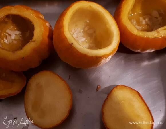 Срежьте верхушки у тыкв, вычистите семечки и мякоть, натрите тыквы внутри маслом с чесноком и поставьте в духовку при 180°C примерно на 35 минут.