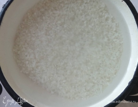 Сначала нужно подготовить рис. Высыпаем рис в достаточно большую емкость, заливаем питьевой водой и аккуратно перетираем зерна, чтобы освободить рис от шелухи и пыли. Вода станет мутной, сливаем воду, заливаем свежую и повторяем процедуру до тех пор, пока вода не станет прозрачной. У меня это обычно 4–5 раз. Затем воду вылить и чуть-чуть обсушить рис в сите. Залить водой еще раз. Оставьте минимум на 20 минут, а лучше на час.