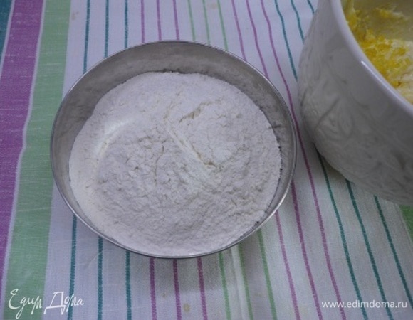 Муку соединяем с разрыхлителем и просеиваем в емкость к творожной массе. Замешиваем тесто, собирая его в единую пластичную массу.