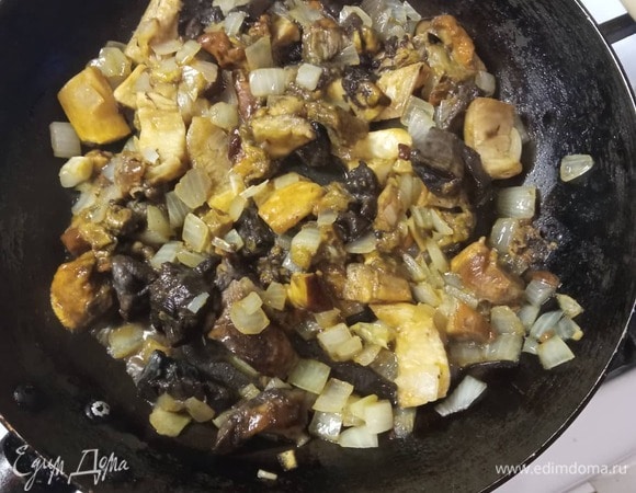 Разморозить грибы. Если у вас свежие или сушеные, нужно предварительно отварить их минут 30. В масле обжарить мелко нашинкованный лук 2 минуты, добавить нарезанные грибы и обжаривать 10 минут.