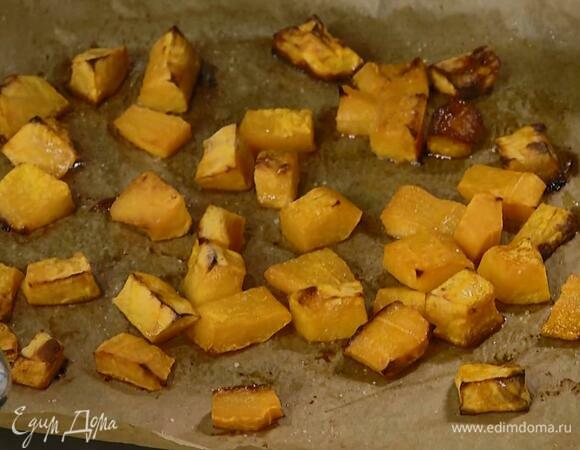 Тыкву почистить и нарезать кубиками, затем выложить на выстеленный бумагой для выпечки противень, посолить, полить оливковым маслом и запекать в разогретой духовке 15–20 минут.