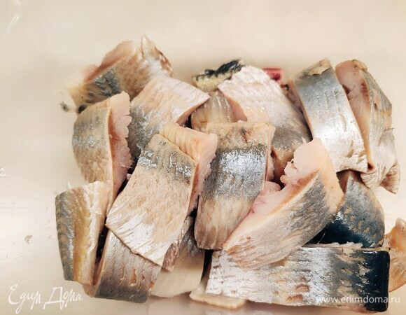 Разделайте сельдь: уберите внутренности, удалите косточки и снимите кожу. Нарежьте филе на кусочки.