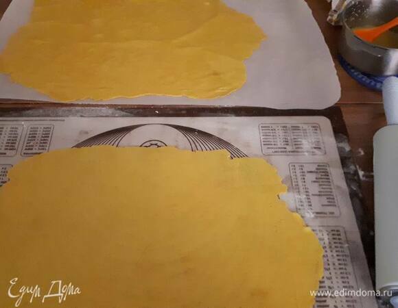 Разделите тесто на 9 частей (по традиции, а так можно больше или меньше). Раскатайте каждую часть до 1 мм толщиной, стараясь придать прямоугольную форму. Намотайте раскатанное тесто на скалку и перенесите на пергамент. Затем смажьте тесто маслом. Раскатайте следующую часть и выложите поверх. И т. д.