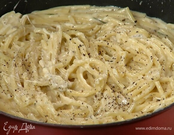 Сырный соус влить в сковороду с макаронами, перемешать и, прогревая на маленьком огне, дать лишней жидкости выпариться, затем снять с плиты и вымешивать еще некоторое время, в конце добавить оставшийся черный перец.