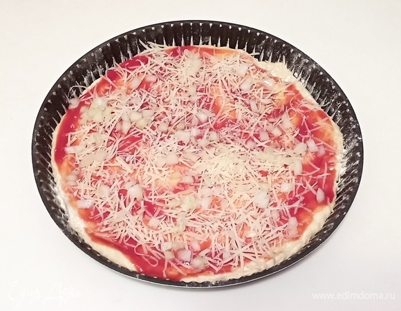 Противень смажьте растительным маслом, чуть посыпьте блинной мукой и раскатайте тесто. Затем выложите на него протертые помидоры, посыпьте сыром и выложите нарезанный кубиками репчатый лук.