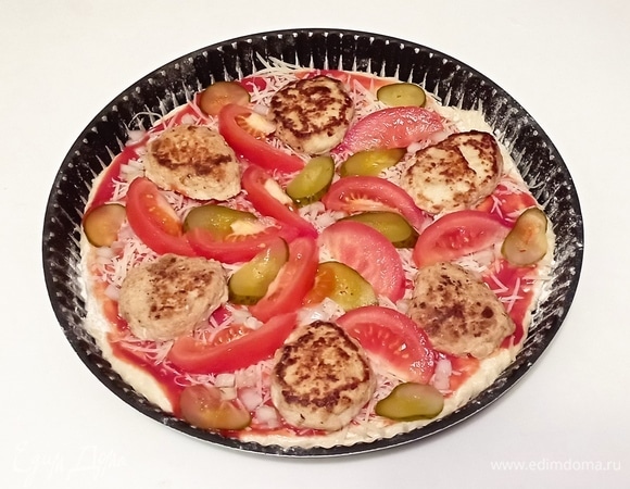 Затем уложите дольки помидора и кружочки соленого огурца.