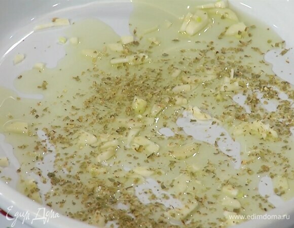 Чеснок почистить, мелко порубить и высыпать в жаропрочную керамическую форму, влить немного оливкового масла, посыпать оставшимся орегано.