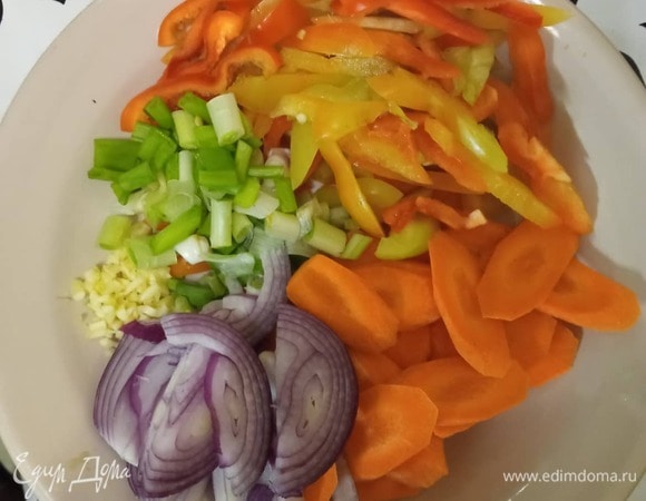 Подготовить овощи. Морковь нарезать тонкими пластинками, перец — полосками, лук — тонкими полукольцами, зеленый лук — кусочками по 2–3 см. Мелко порубить чеснок.
