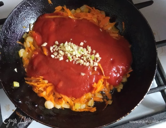 Добавляем пассату и мелко рубленный чеснок. Перемешиваем и обжариваем еще 2–3 минуты.