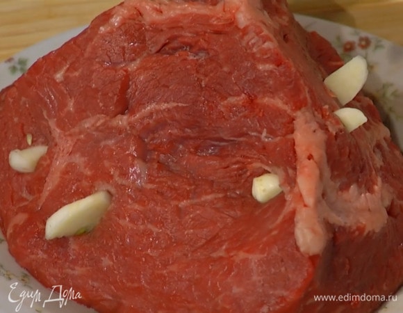По всей поверхности мяса сделать кончиком ножа надрезы и вставить в них часть чеснока.