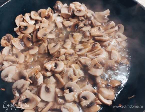 К луку добавить нарезанные пластинами шампиньоны. Жарить, пока не выпарится жидкость и грибы не подрумянятся.