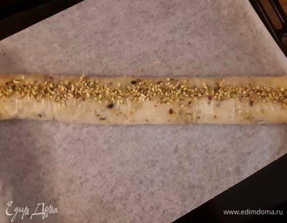 Заверните в рулет. Хорошо зафиксируйте края. Смажьте рулет остатками масла и посыпьте фисташками.