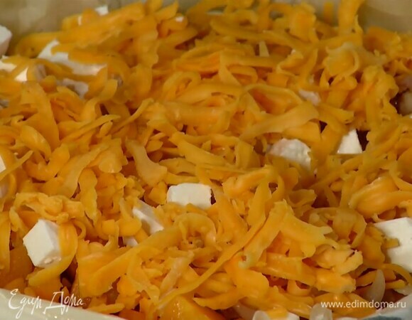 Чеддер натереть на крупной терке, половиной посыпать начинку и слегка утопить сыр.