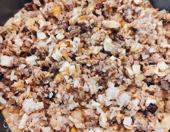 На дно формы вылить половину теста. Выложить всю начинку и равномерно разровнять.