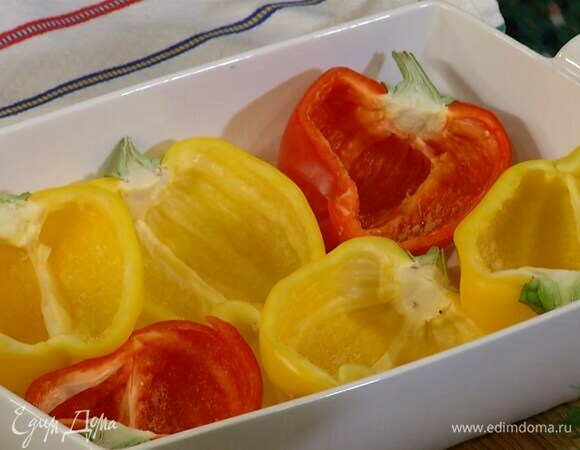 Перец, сохранив плодоножку, разрезать вдоль пополам, удалить семена и выложить в жаропрочную форму срезами вверх.
