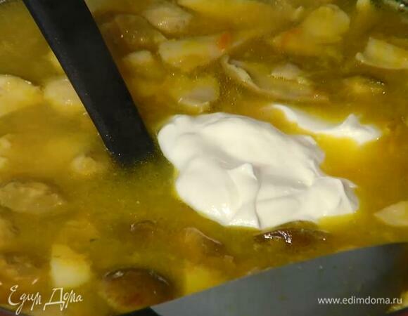 Когда картофель будет почти готов, добавить маринованные грибы и варить еще пару минут, затем выключить огонь, добавить в суп часть сметаны и перемешать.