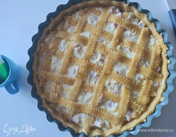 Выложить начинку. Раскатать оставшиеся тесто, нарезать на полоски, уложить сверху начинки и смазать оливковым маслом.