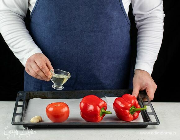 Болгарский перец, помидоры и чеснок выложите на противень, застеленный пергаментом. Сбрызните оливковым маслом и запекайте в духовке при 180°С примерно 25–30 минут.