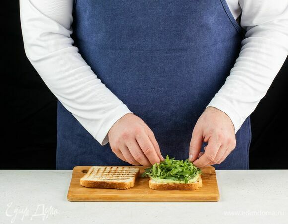 Выложите на два ломтика мусс из авокадо и плавленого сыра, затем положите руколу.