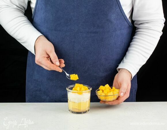 Следующим слоем выложите творожный сыр с лимонным соком, а сверху — кусочки манго. Если манго не осталось, для украшения можно использовать ломтики ананаса или любые другие ягоды и фрукты.