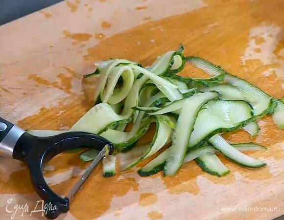Огурцы с помощью овощечистки нарезать тонкими полосками, середину с семенами не нарезать.
