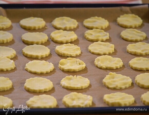 Кондитерскими формочками вырезать из теста фигурки и выложить на выстеленный бумагой для выпечки противень.