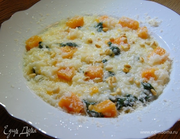 Готовое ризотто выложить в большое блюдо, посыпать половиной сыра и перемешать, украсить подсушенными орехами. Оставшийся сыр подать на стол.