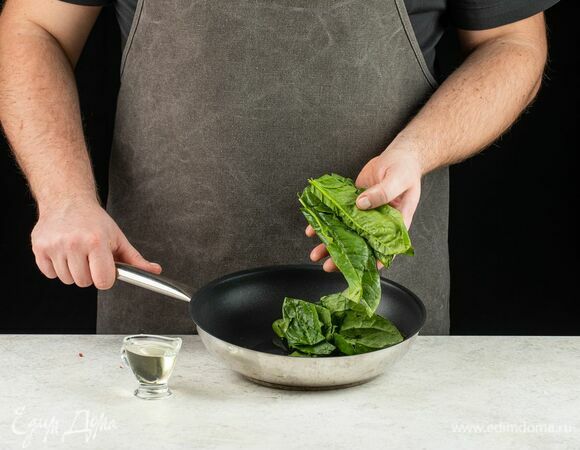 На сковороде разогрейте немного растительного масла. Промойте шпинат и положите на сковороду. Тушите 5 минут, помешивая, до уменьшения зелени в объеме.
