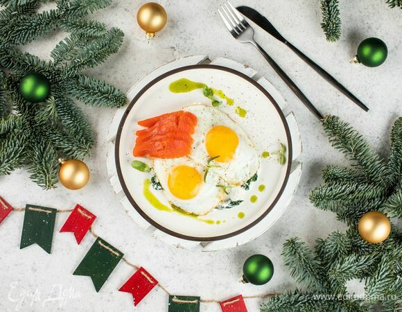 На тарелку выложите шпинат, на него — глазунью, а рядом положите кусочки слабосоленой рыбы.