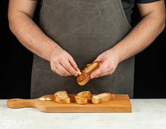 Каждый ломтик хлеба натрите разрезанным пополам зубчиком чеснока.