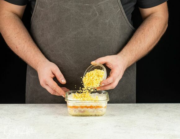 Завершите салат слоем тертого яичного желтка и украсьте сверху измельченным зеленым луком.