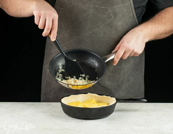 Форму для выпечки смажьте маслом. Тесто разделите на две части: одну побольше и вторую поменьше. <br />
Часть побольше раскатайте и поместите в форму для выпечки. Выложите слой картофеля на тесто.