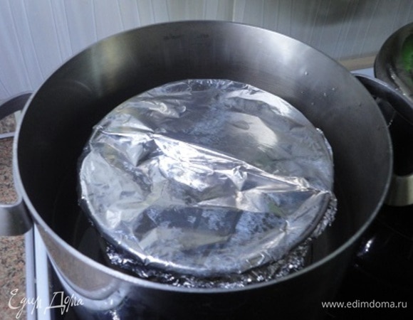 Поместите форму в кастрюлю, на дне которой лежит решетка. Налейте воду до половины высоты формы и закройте плотно крышкой. Готовьте пудинг на водяной бане не менее 3 часов при умеренном кипении. Следите за уровнем воды и подливайте по необходимости.