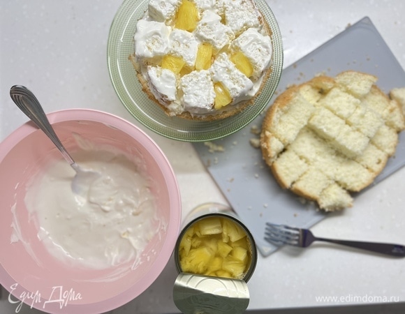 Сметану взбить с сахаром. Смазать верхушку кремом (она будет основанием). Поочередно смазывать каждый кубик бисквита кремом и укладывать горкой в виде елочки на бисквитную основу. В промежутках добавлять кусочки ананаса.